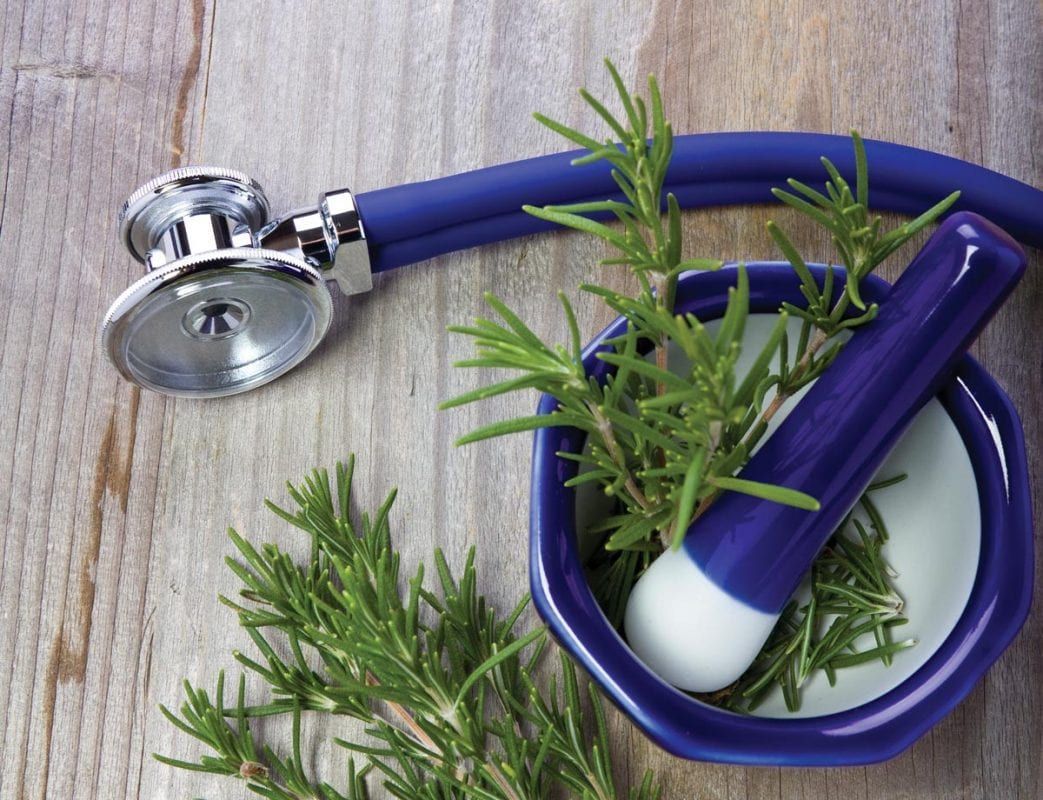 a stethoscope is sitting next to a mortar and pestle filled with herbs .