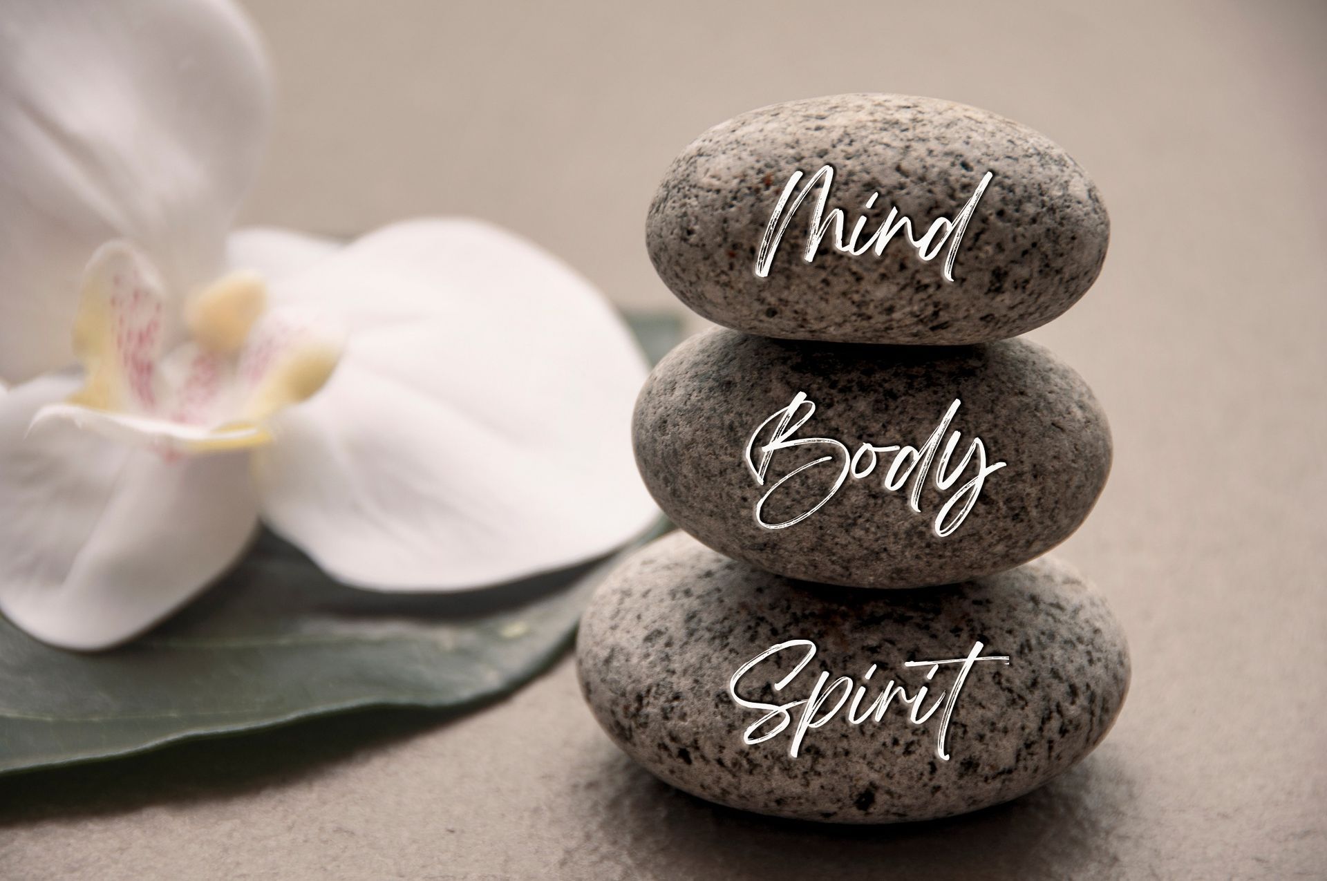 three rocks stacked on top of each other with the words mind body spirit written on them .