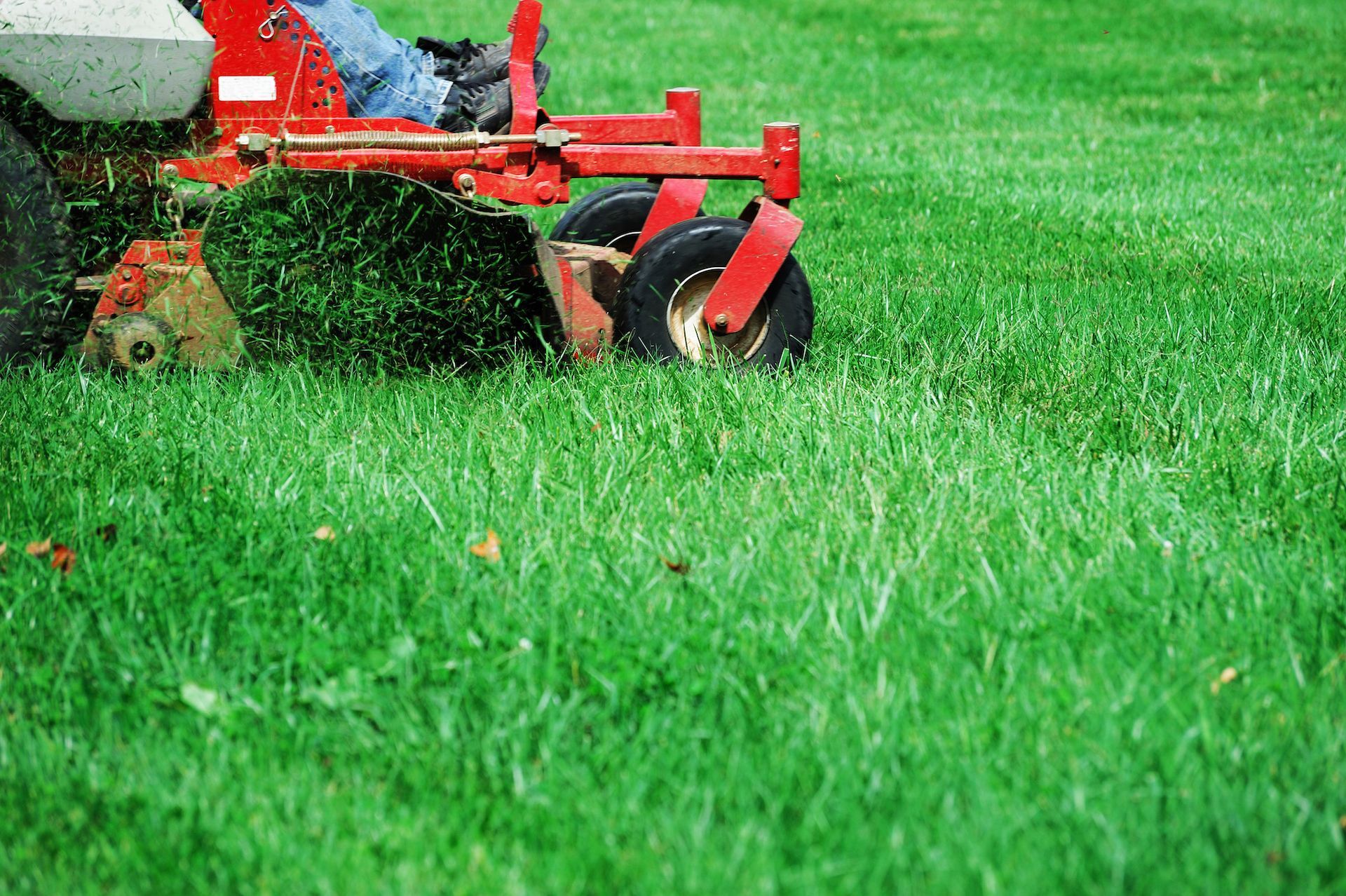 a person is riding a red lawn mower on a lush green lawn