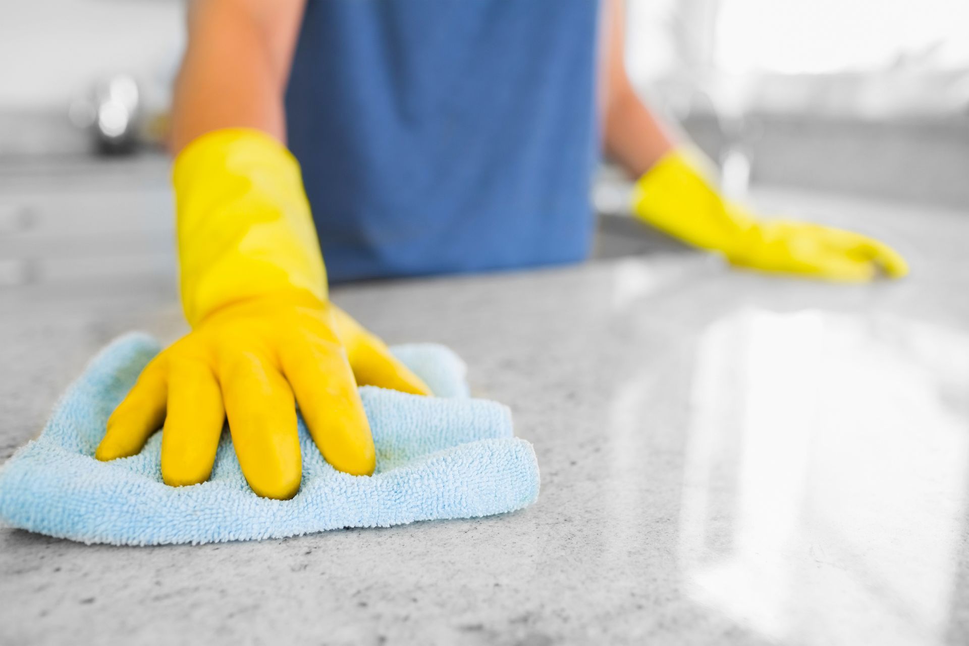 a person wearing yellow gloves is cleaning a counter with a blue cloth