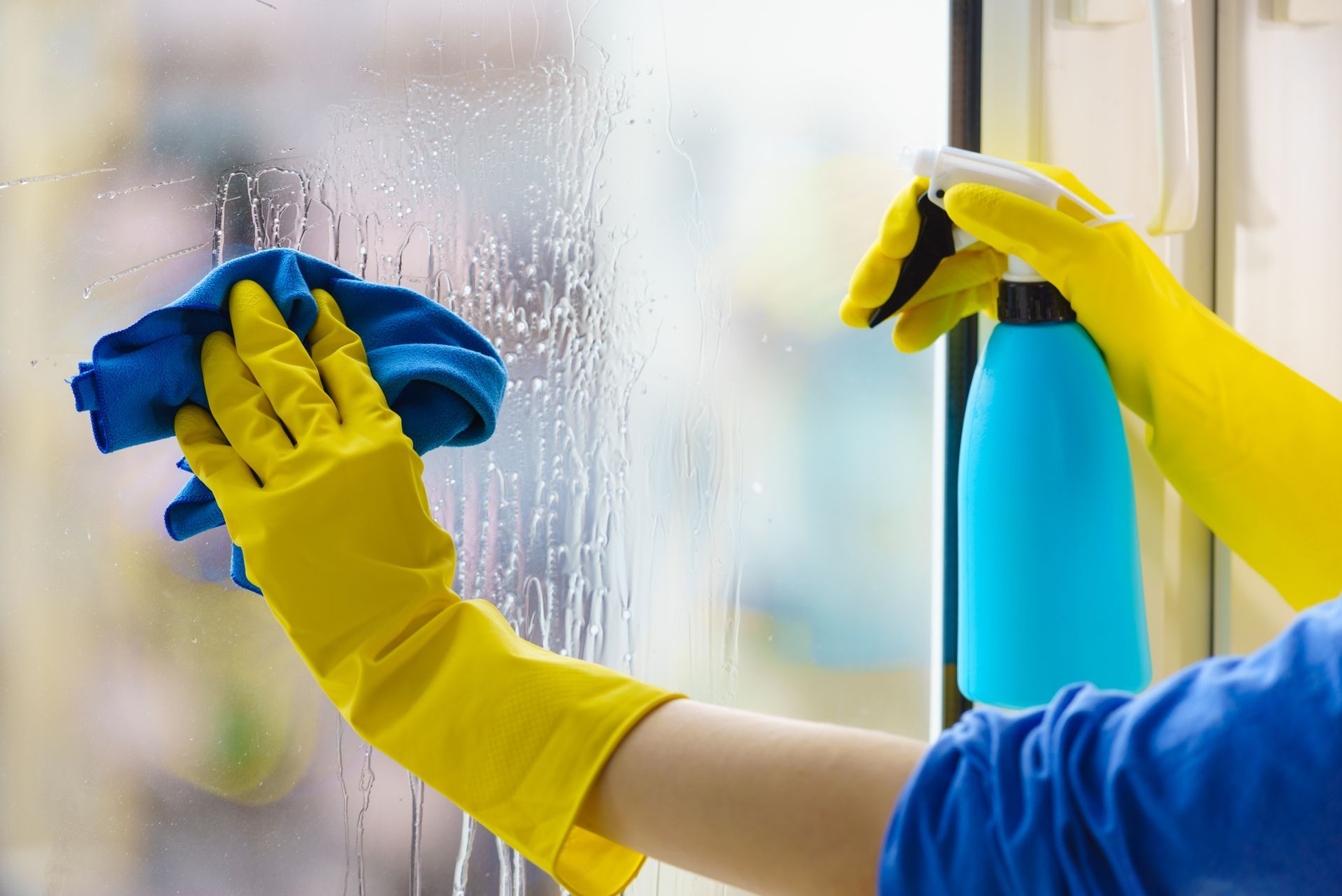 a person wearing yellow gloves is cleaning a window