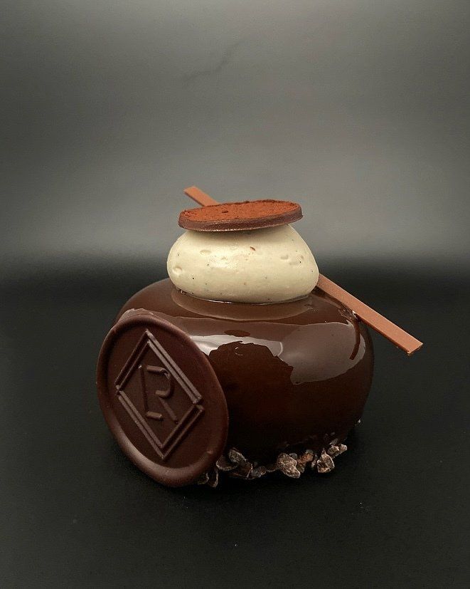Dessert glacé au chocolat avec glaçage blanc et accents de chocolat, sur fond noir.