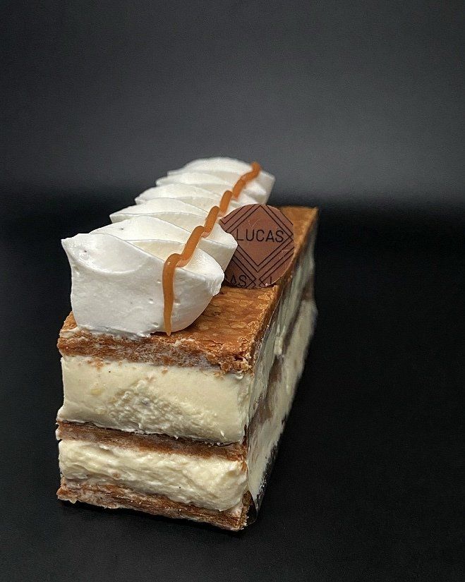 Dessert crémeux en couches avec meringue, filet de caramel et logo, sur une surface noire.