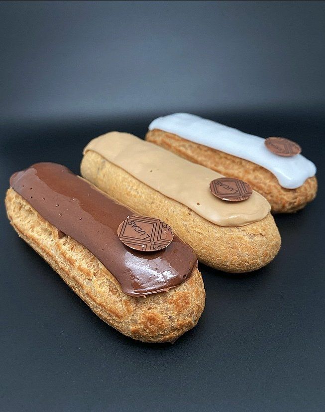 Trois éclairs, chacun avec un glaçage de couleur différente : marron, beige et blanc, sur fond noir.