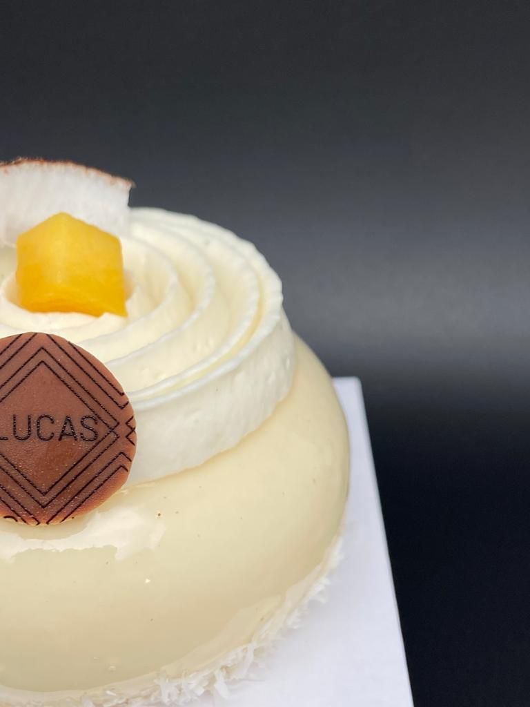 Gâteau glacé blanc avec tourbillon de crème, cube de mangue, disque de chocolat.