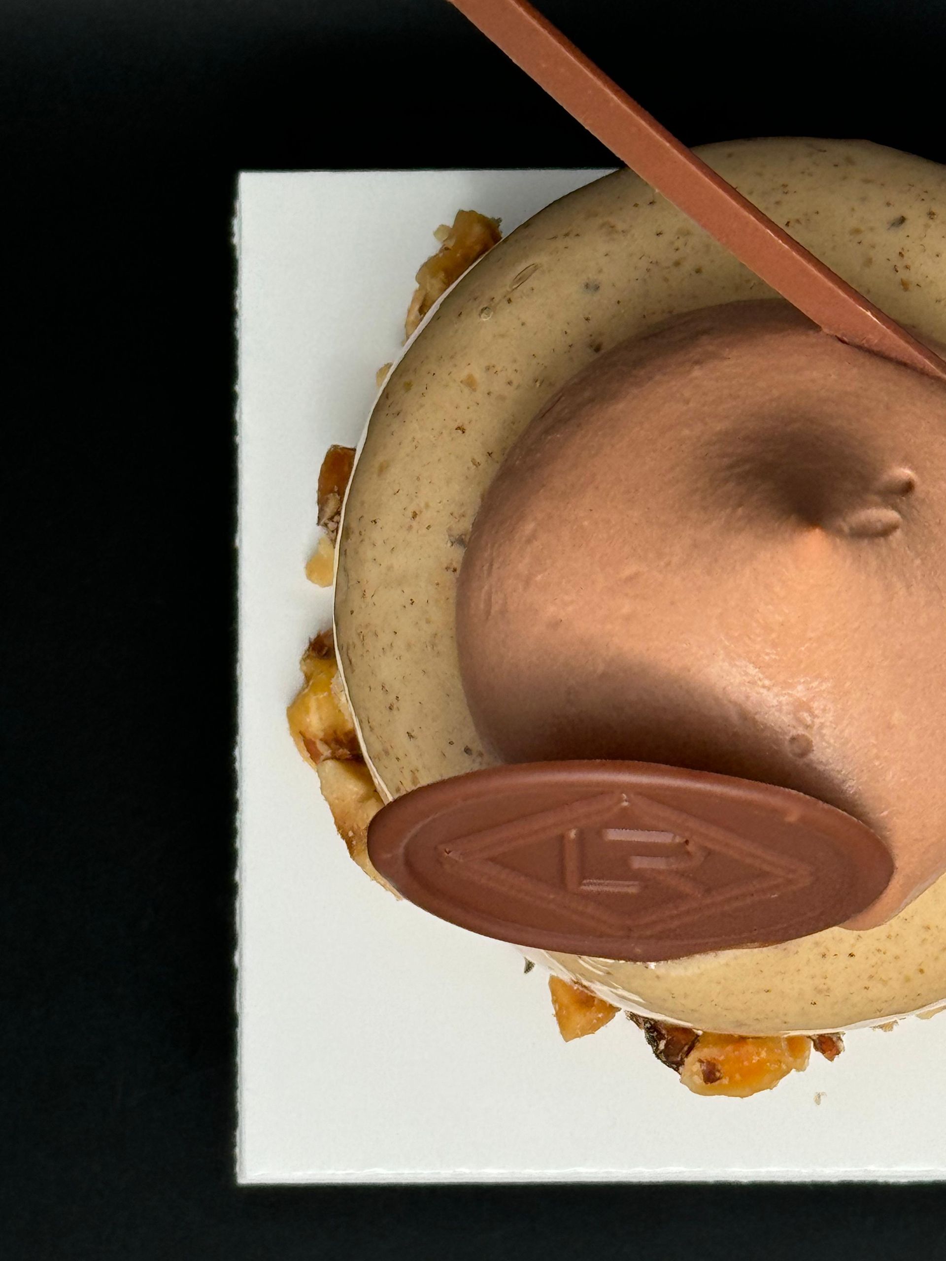 Dessert élégant avec mousse au caramel, accents de chocolat et noix sur une assiette blanche.