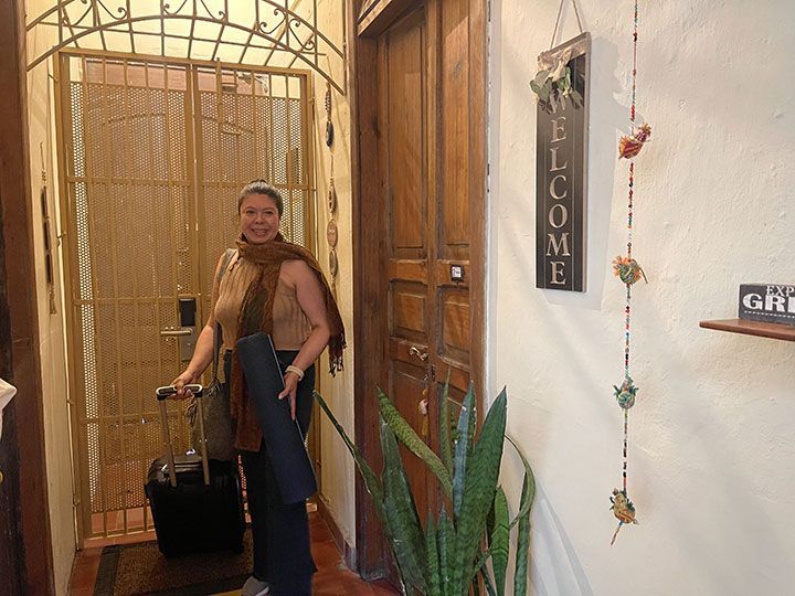 Una mujer está parada frente a un cartel de bienvenida.