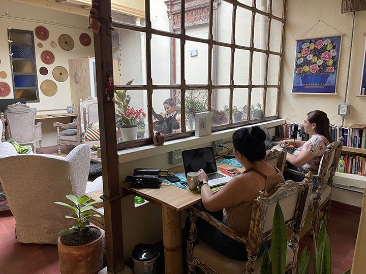 Una mujer está sentada en un escritorio en una habitación con una computadora portátil.