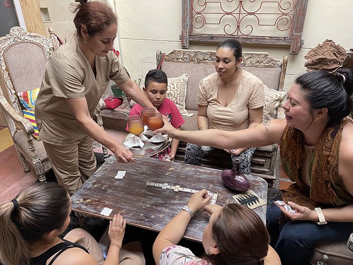 Un grupo de personas está sentada alrededor de una mesa jugando dominó.