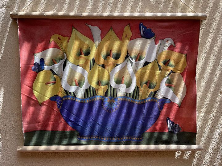 Un cuadro de flores en un cuenco está colgado en una pared.