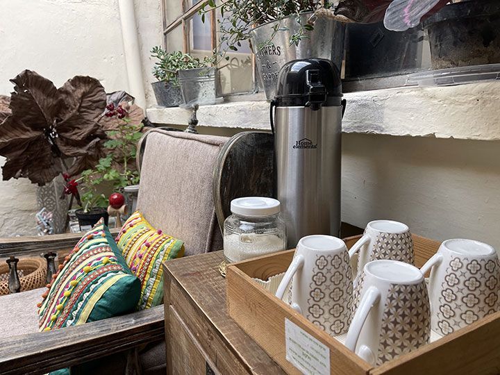 Una caja de madera llena de tazas de café y un termo sobre una mesa.