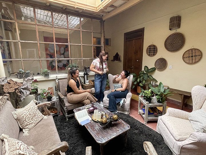 Tres mujeres están sentadas en una sala de estar hablando entre sí.