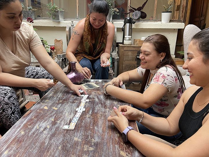 Un grupo de mujeres están sentadas alrededor de una mesa jugando dominó.