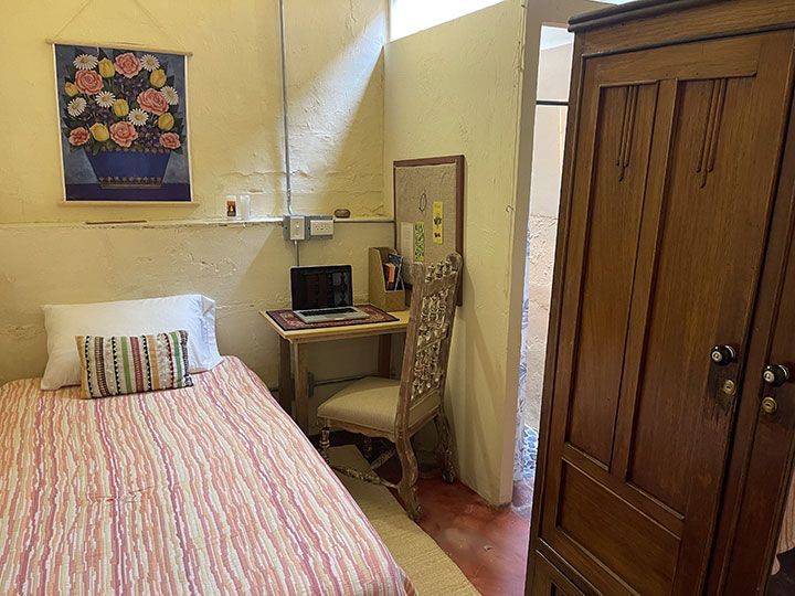 Un dormitorio con una cama individual y un escritorio con una computadora portátil encima.