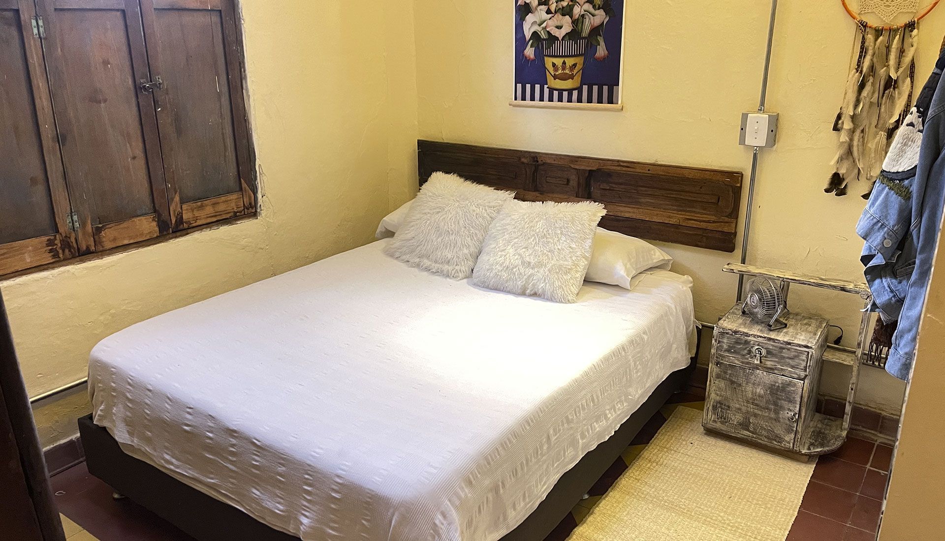 Un dormitorio con cama, mesita de noche y ventana.