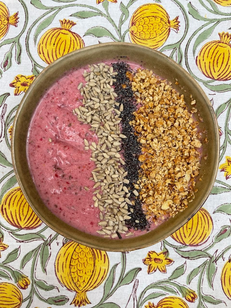 Un tazón de batido con nueces y semillas sobre una mesa.