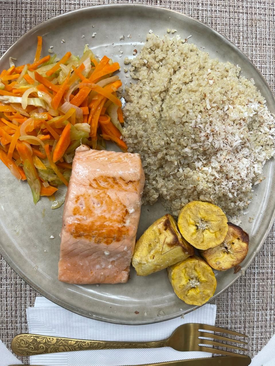 Un plato de comida con arroz, zanahorias y plátanos en una mesa.