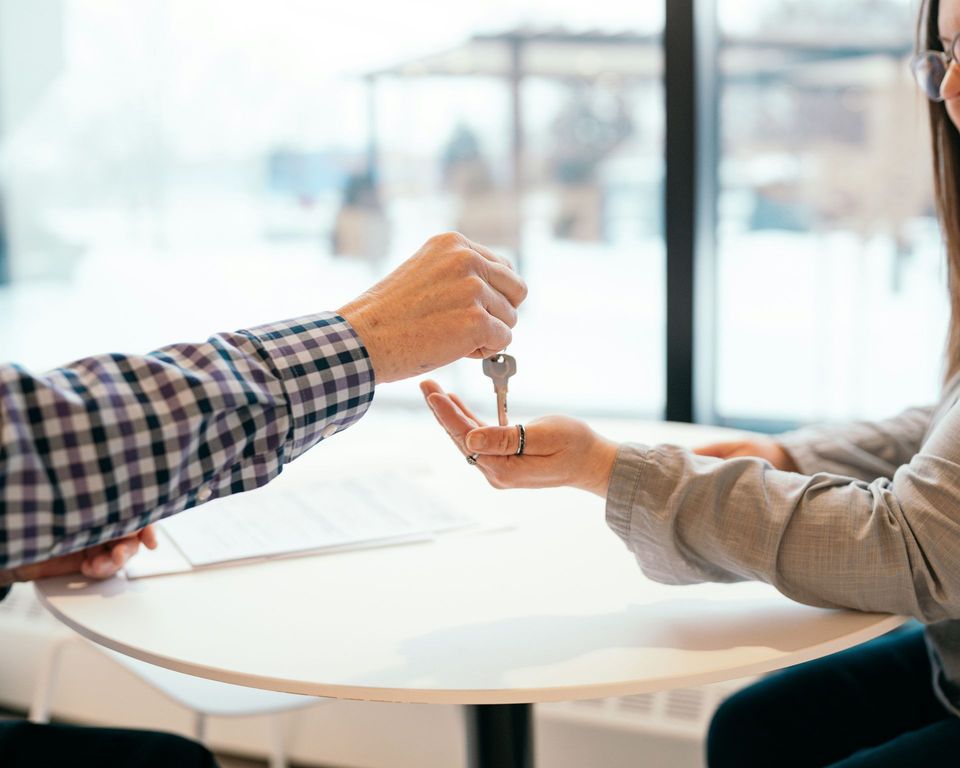 A man is handing a key to a woman at a table.