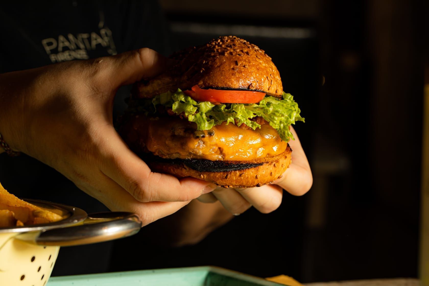 Una persona tiene in mano un hamburger.