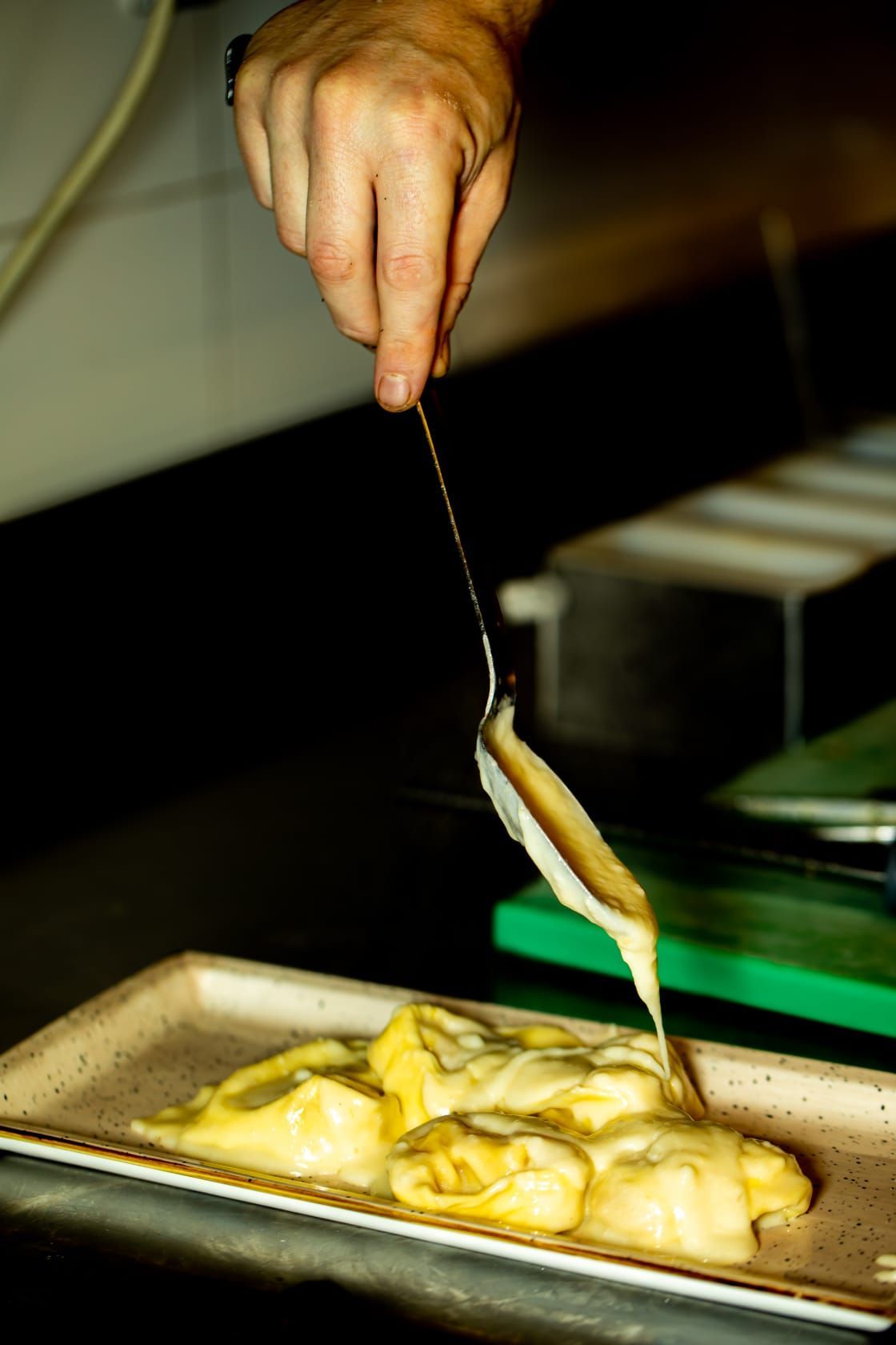 Una persona sta versando la salsa su un piatto di cibo