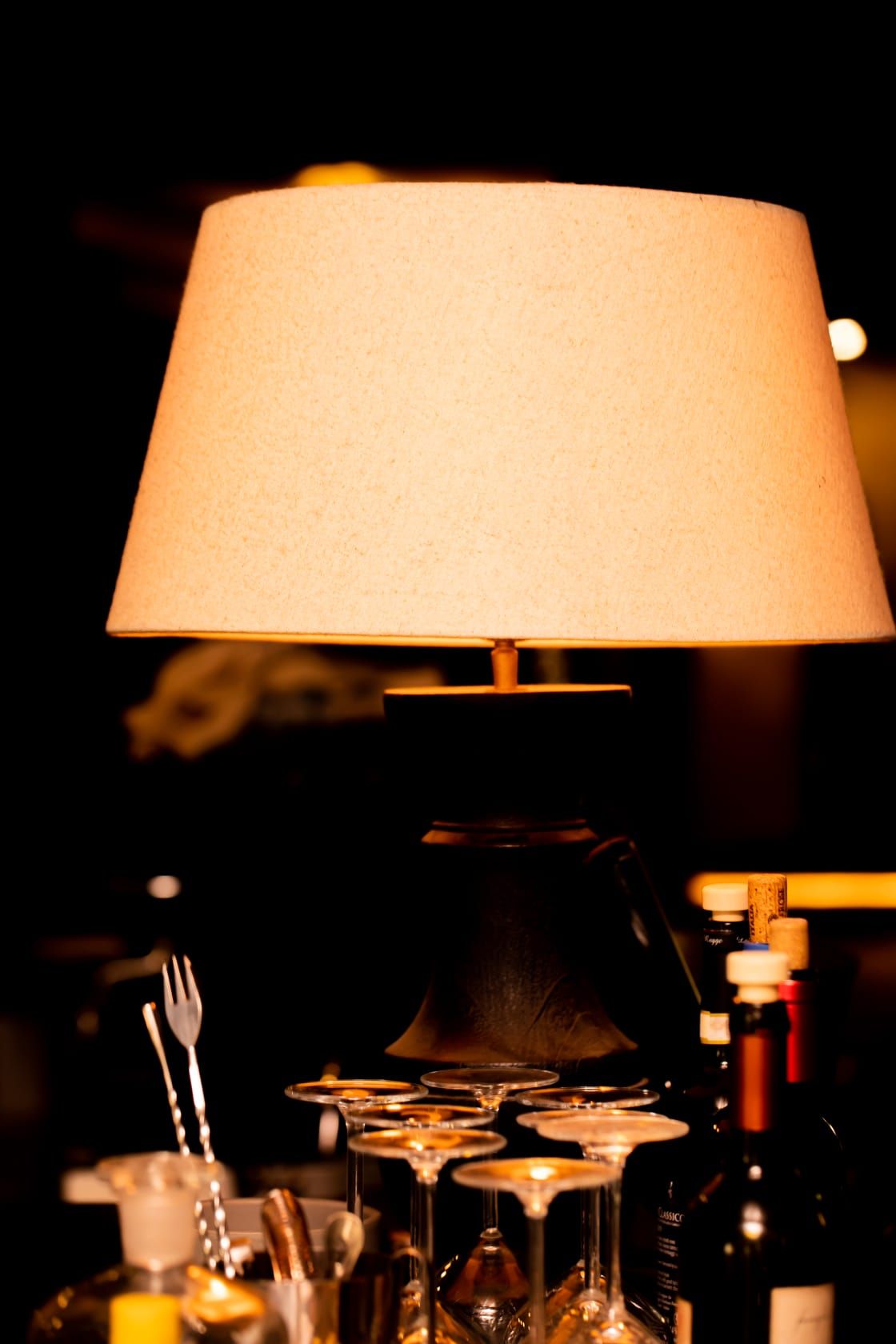 Una lampada con paralume bianco è accesa in una stanza buia.