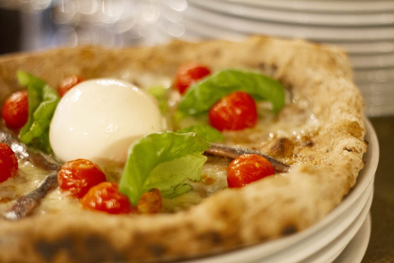 Un primo piano di una pizza con pomodoro e mozzarella su un piatto.