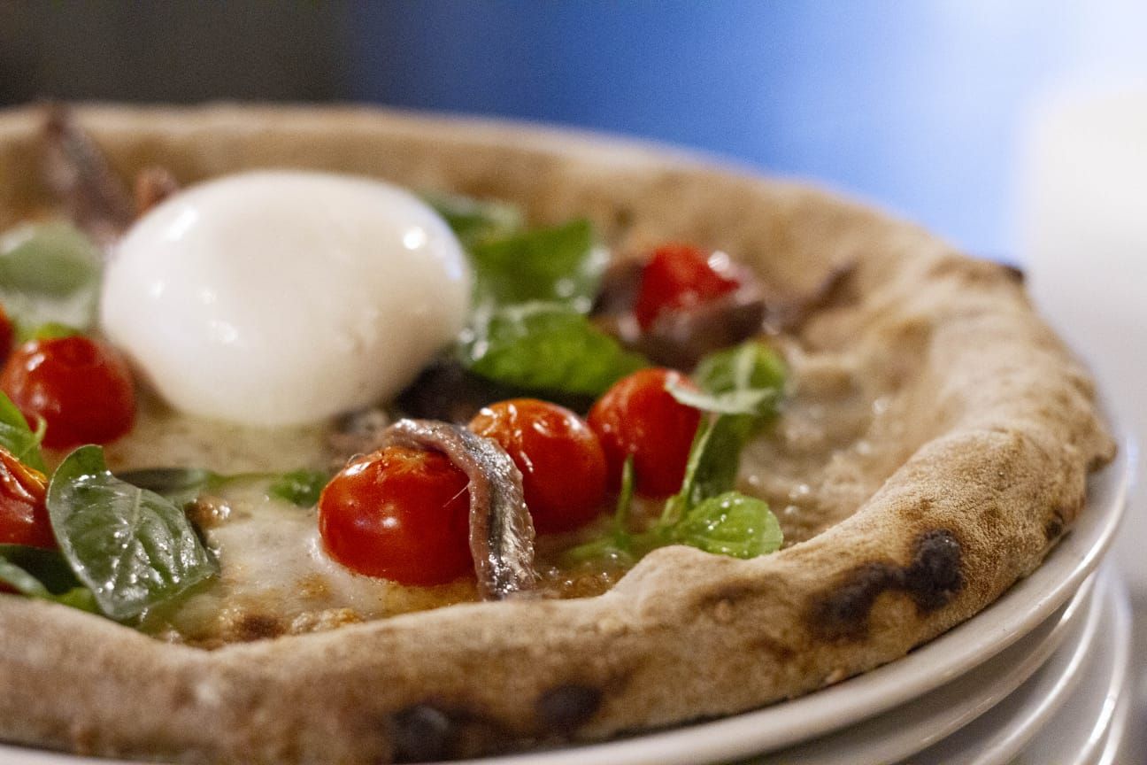 Un primo piano di una pizza con pomodoro e mozzarella su un piatto.