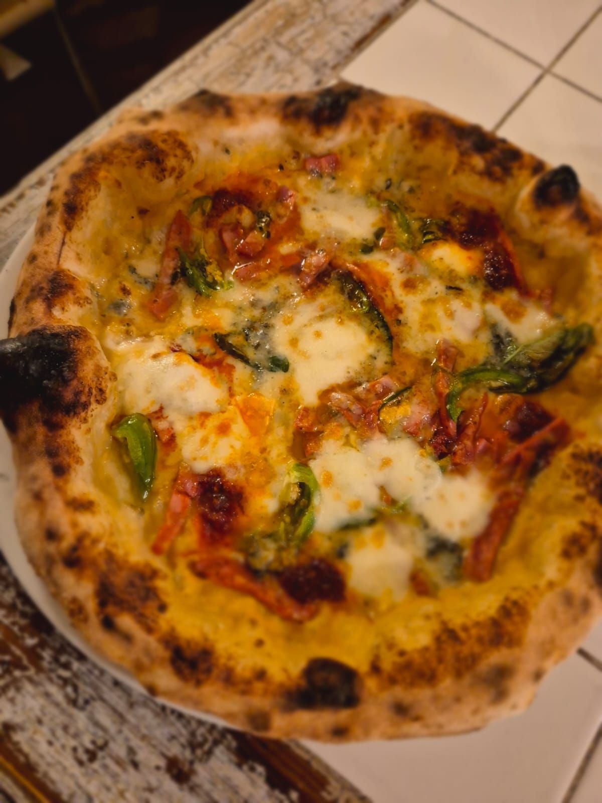 Una pizza è seduta su un piatto bianco su un tavolo.