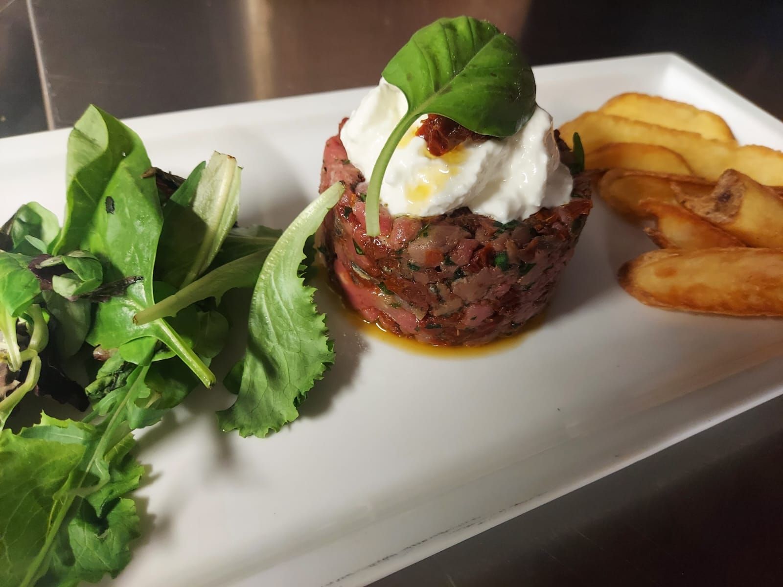 Un piatto di cibo con patatine fritte e un'insalata sopra