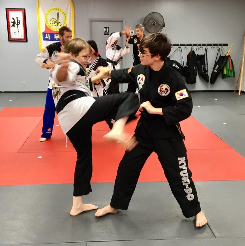 a group of people are practicing martial arts and one of their pants says kyudo