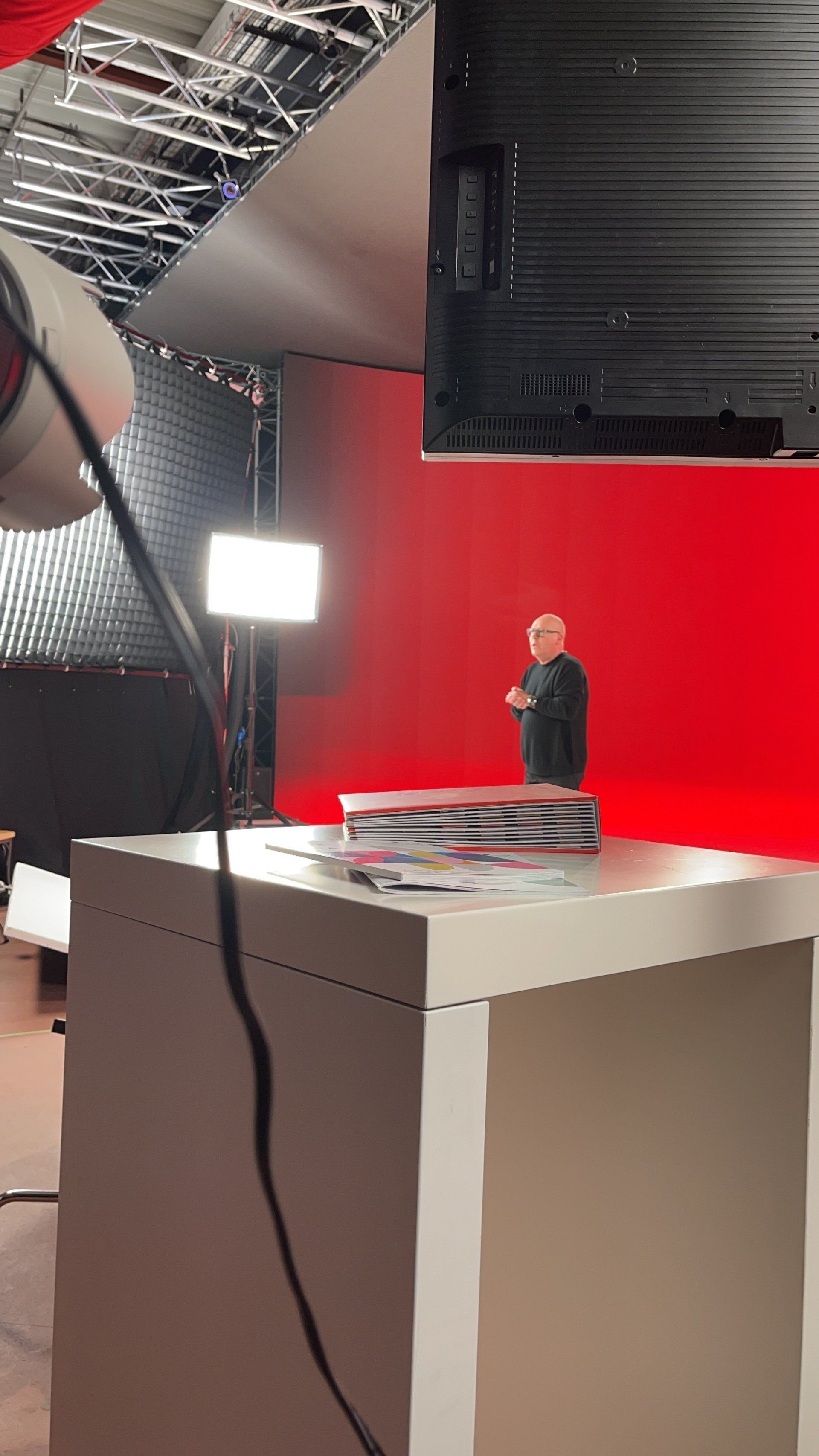 Ein Mann steht in einem Studio vor einem roten Bildschirm.