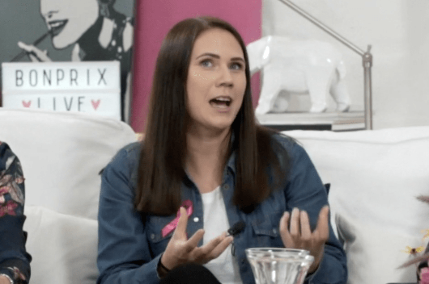 Eine Frau sitzt auf einem Sofa und unterhält sich mit einer anderen Frau.