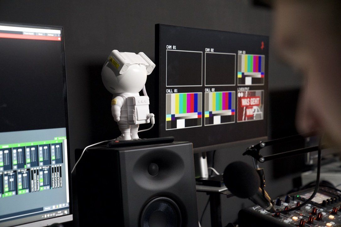 Ein Roboter sitzt auf einem Lautsprecher vor einem Monitor.