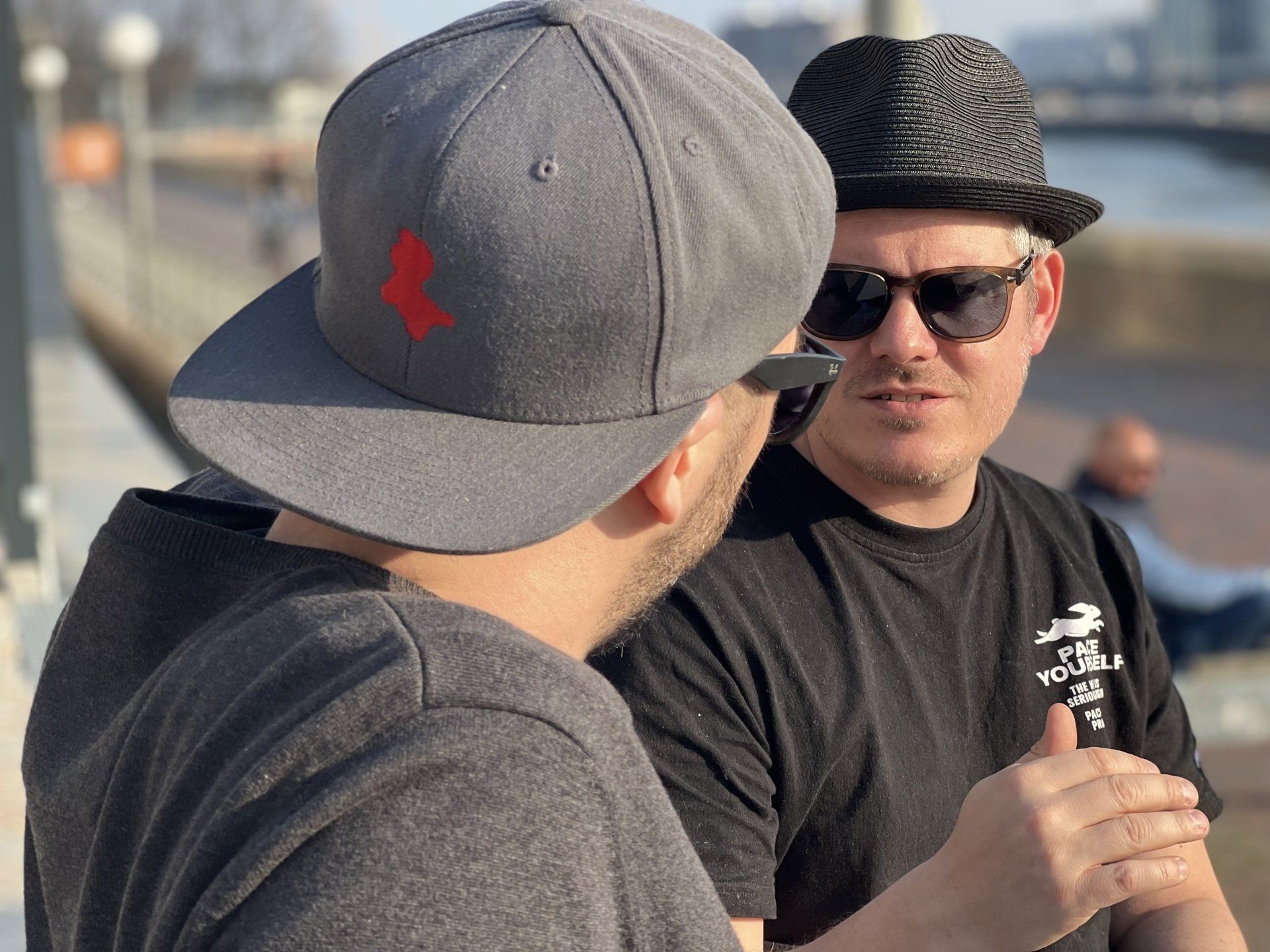 Zwei Männer mit Hüten und Sonnenbrillen unterhalten sich