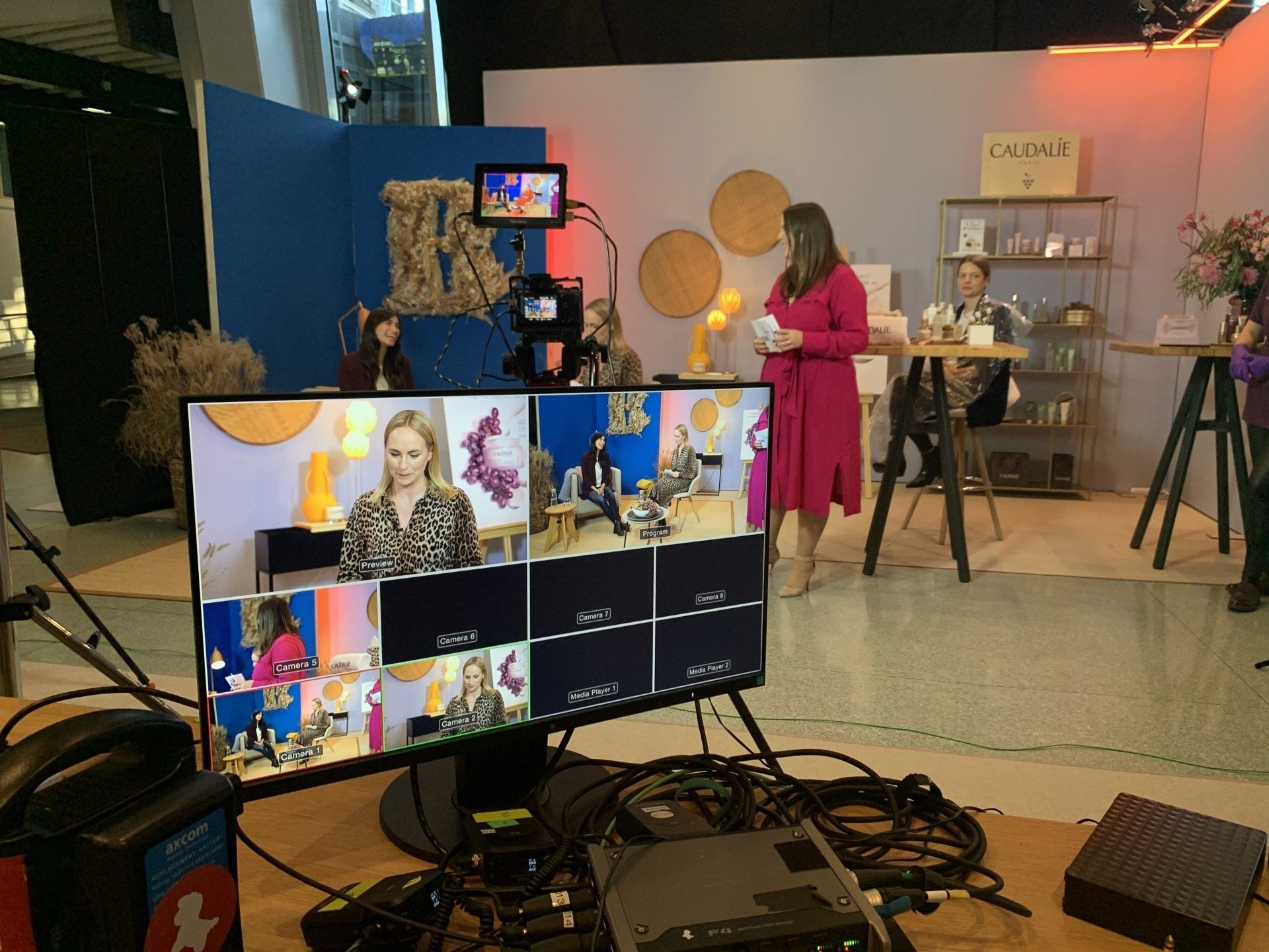 Eine Frau in einem rosa Kleid steht vor einem Computermonitor.