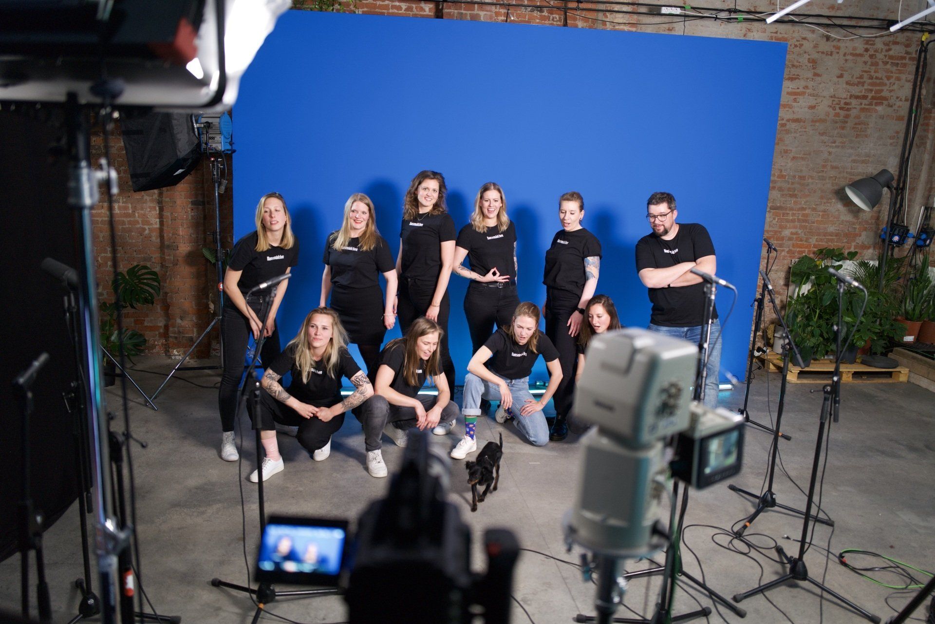 Eine Gruppe von Menschen posiert vor einem blauen Bildschirm für ein Foto.