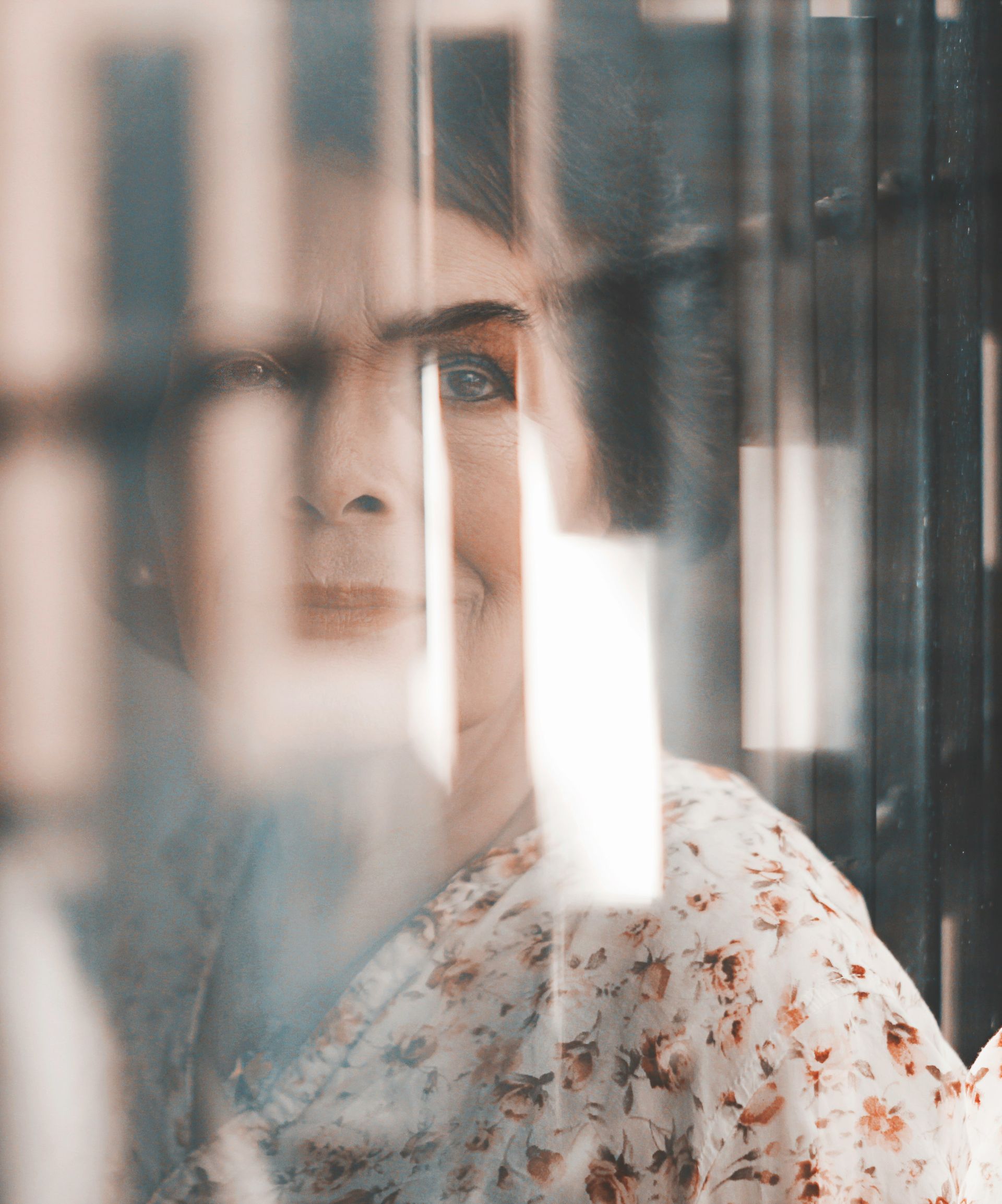 A woman is looking out of a window behind bars.