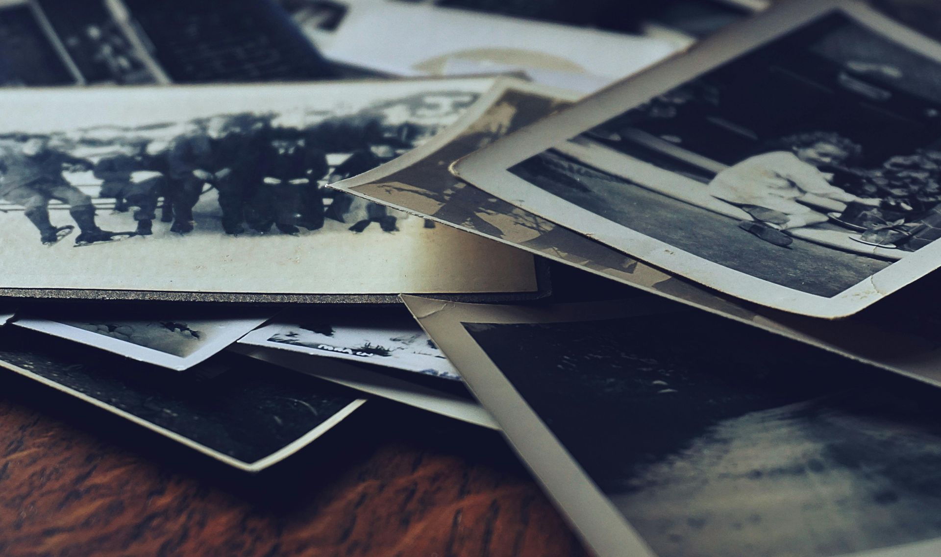 A pile of old photographs on a wooden table