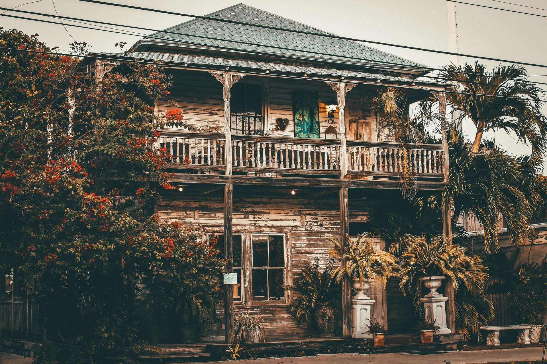An old wooden house with a balcony and trees in front of it