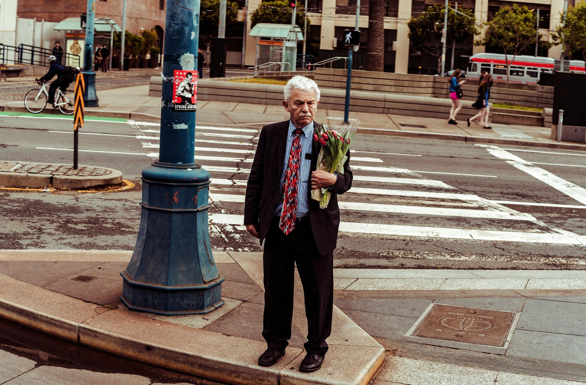 A man in a suit and tie is holding a bouquet of flowers