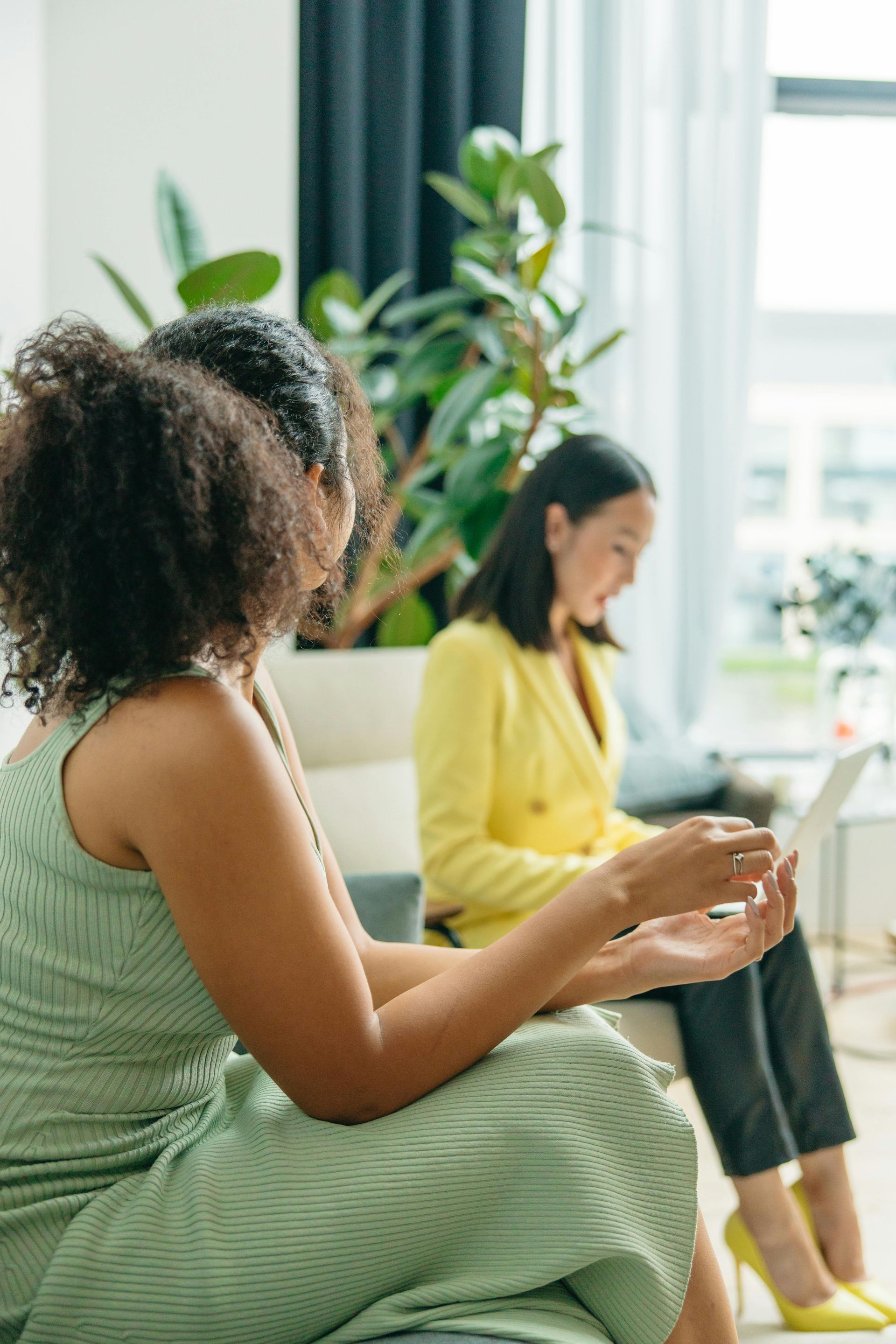Two women are sitting in chairs talking to each other in a living room.