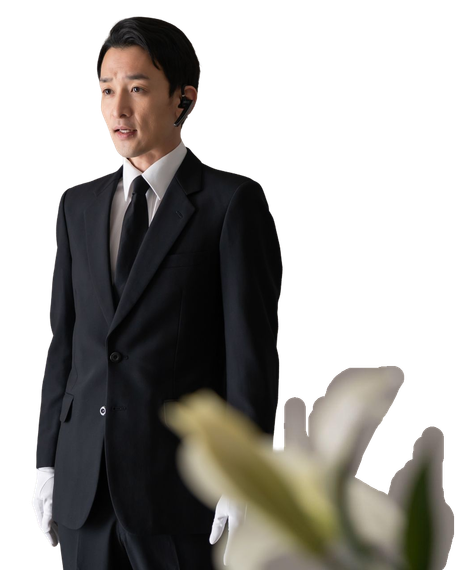 A man in a suit and tie is standing next to a flower.