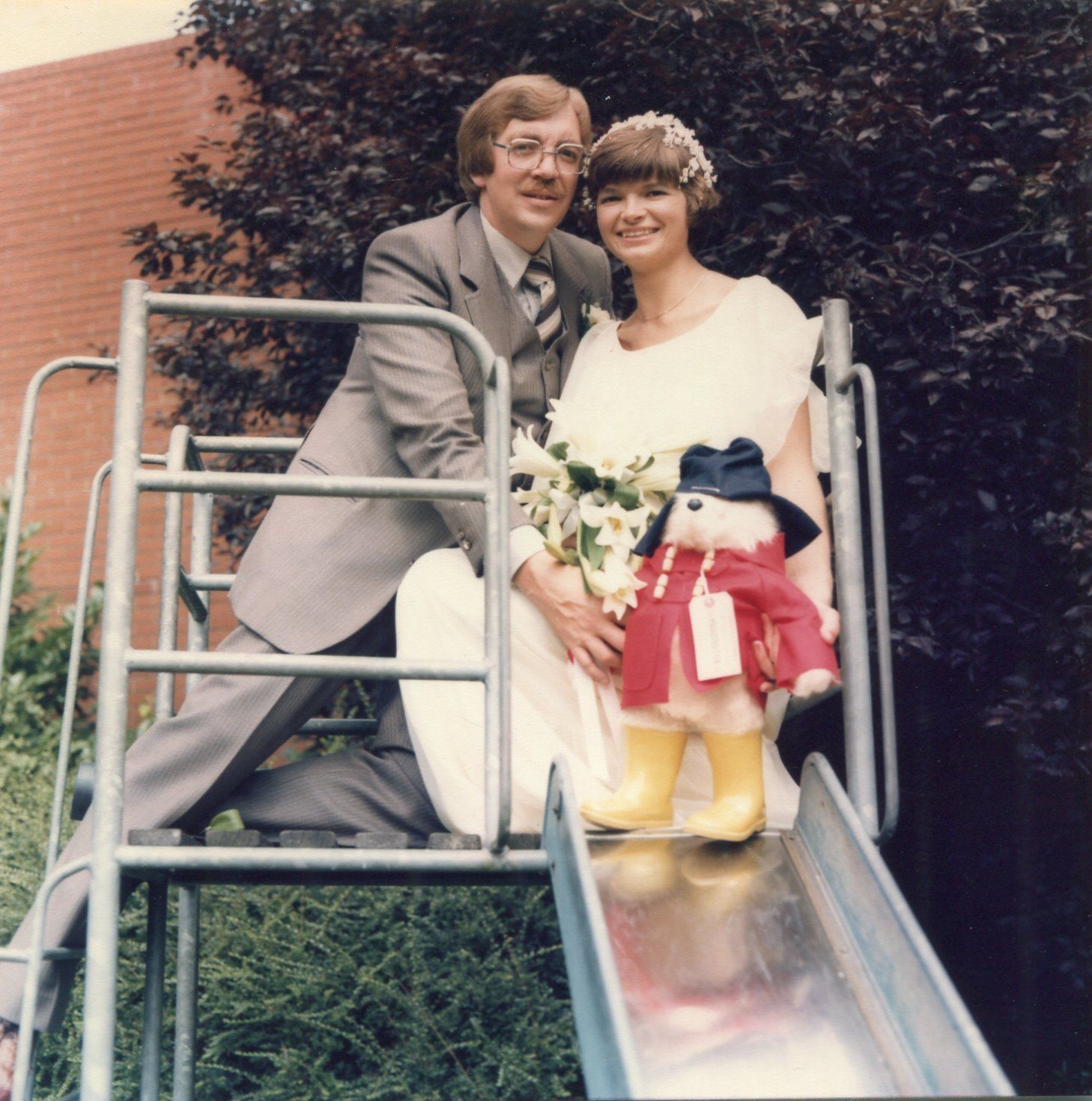 A bride and groom pose for a picture on a slide