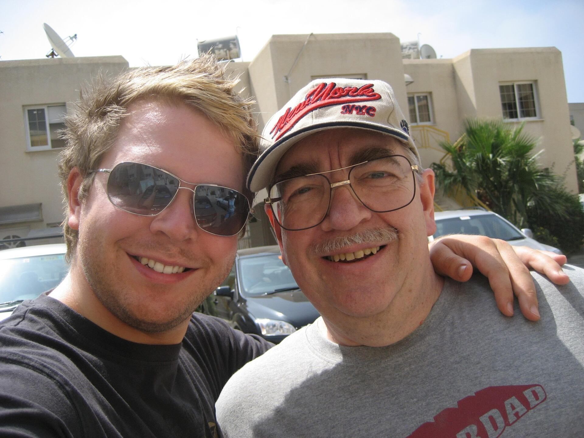 Two men posing for a picture with one wearing a shirt that says dad