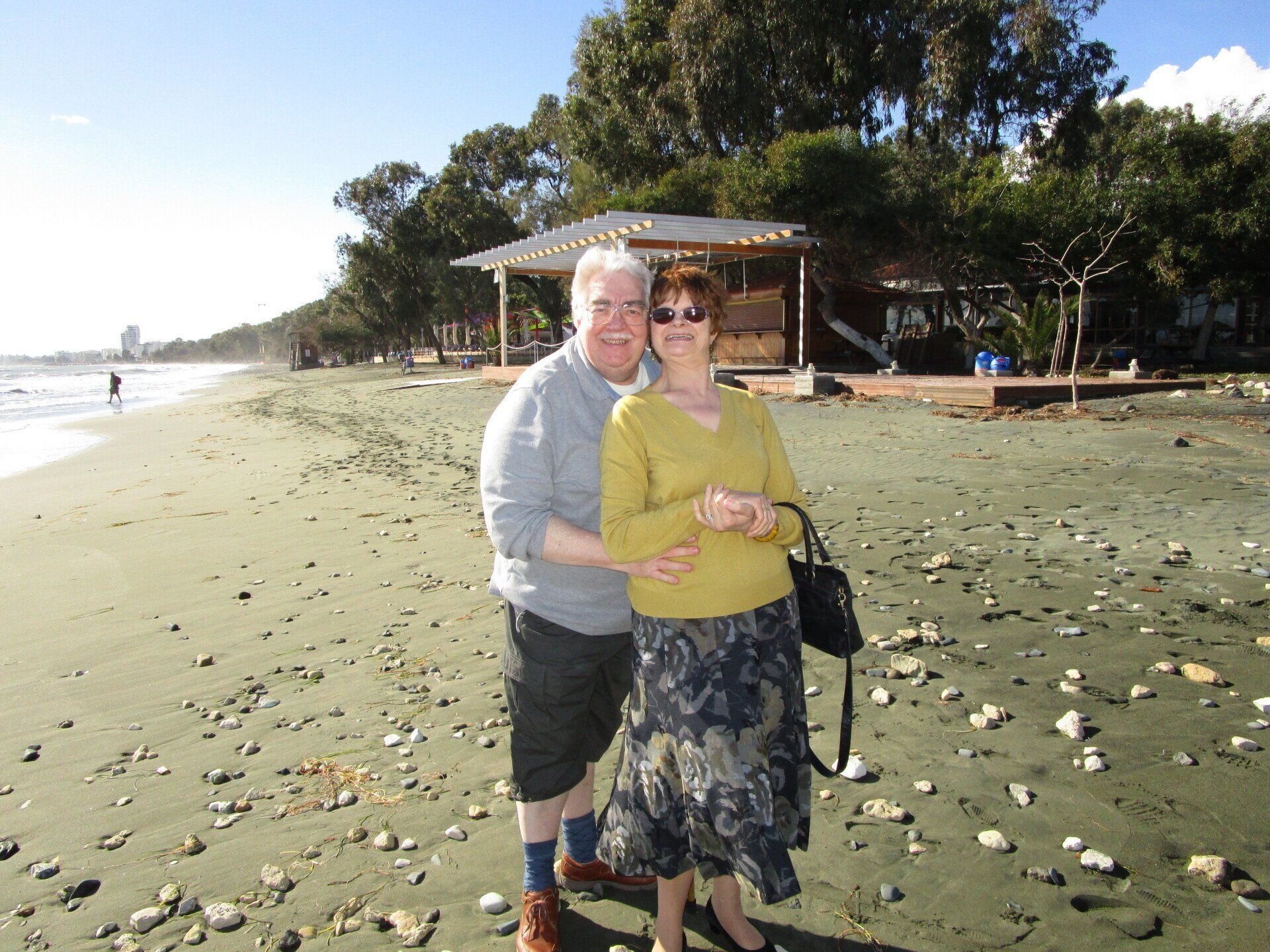A man and woman are posing for a picture on the beach