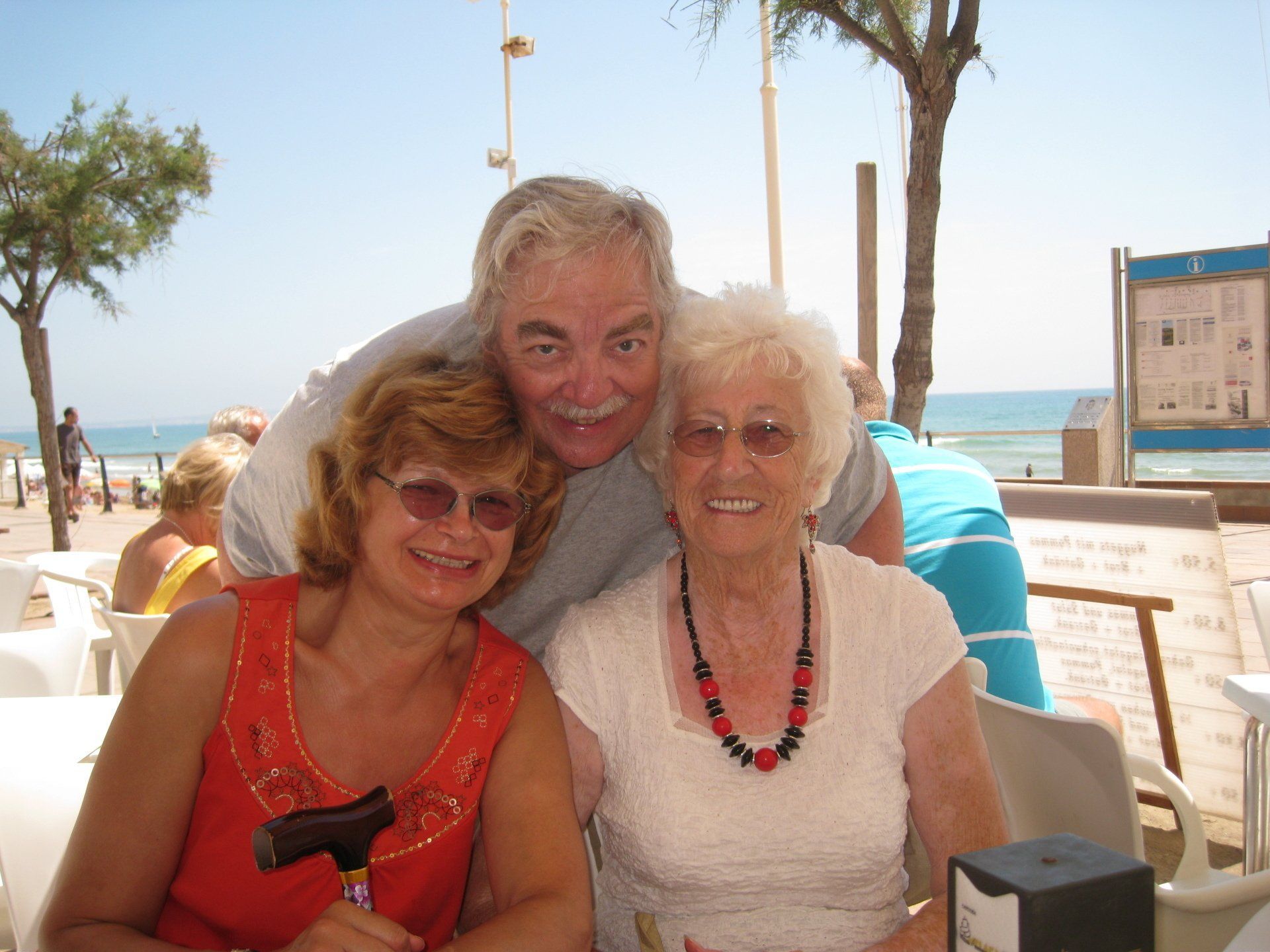A man and two women are posing for a picture on the beach