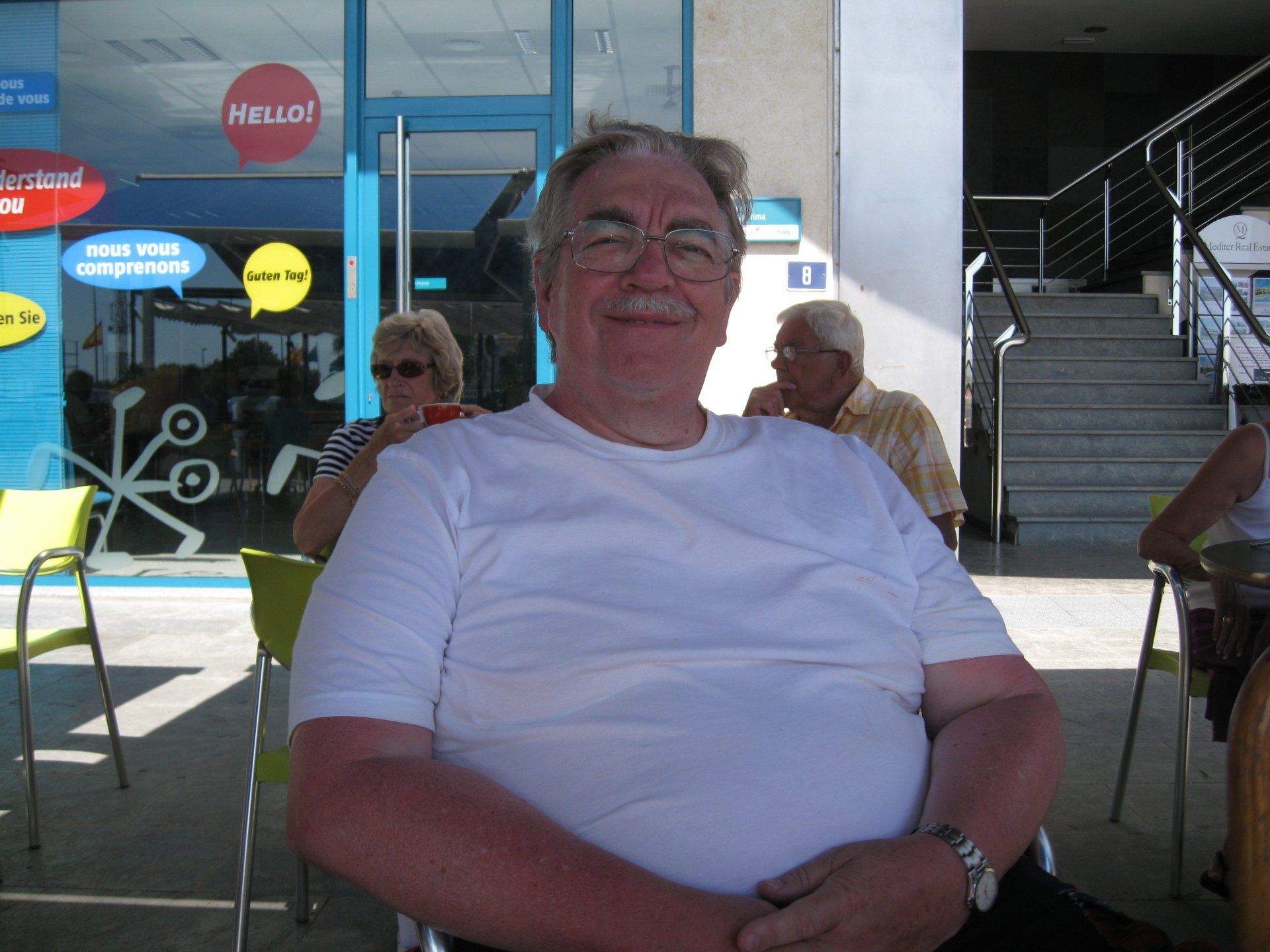 A man sitting in front of a store that says hello