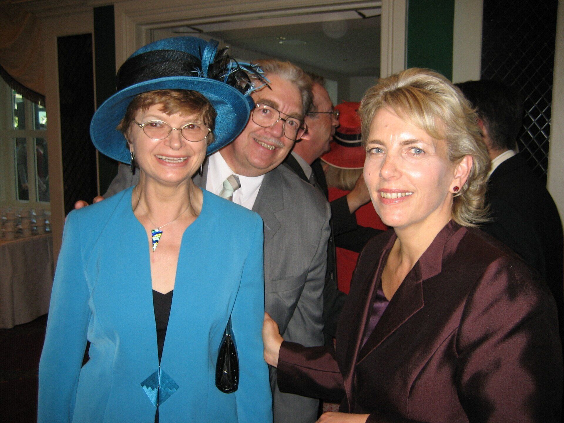 A woman in a blue hat is posing for a picture with two other women