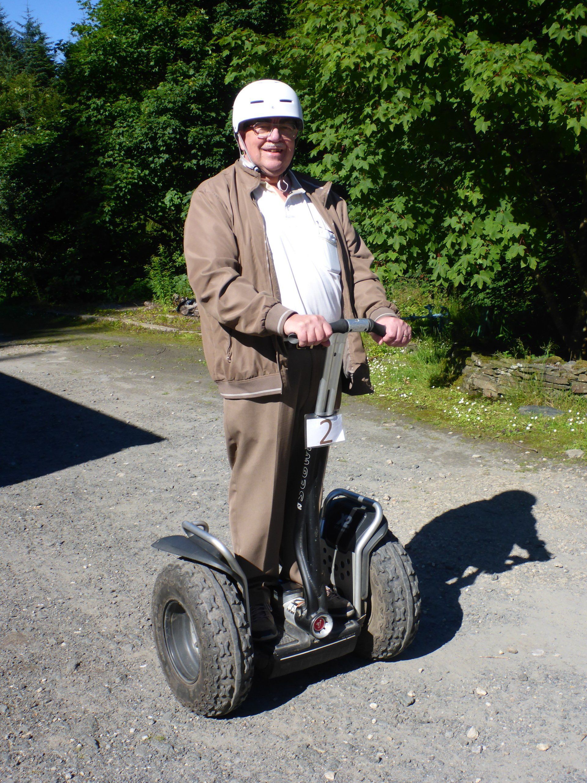 A man wearing a white helmet is riding a segway