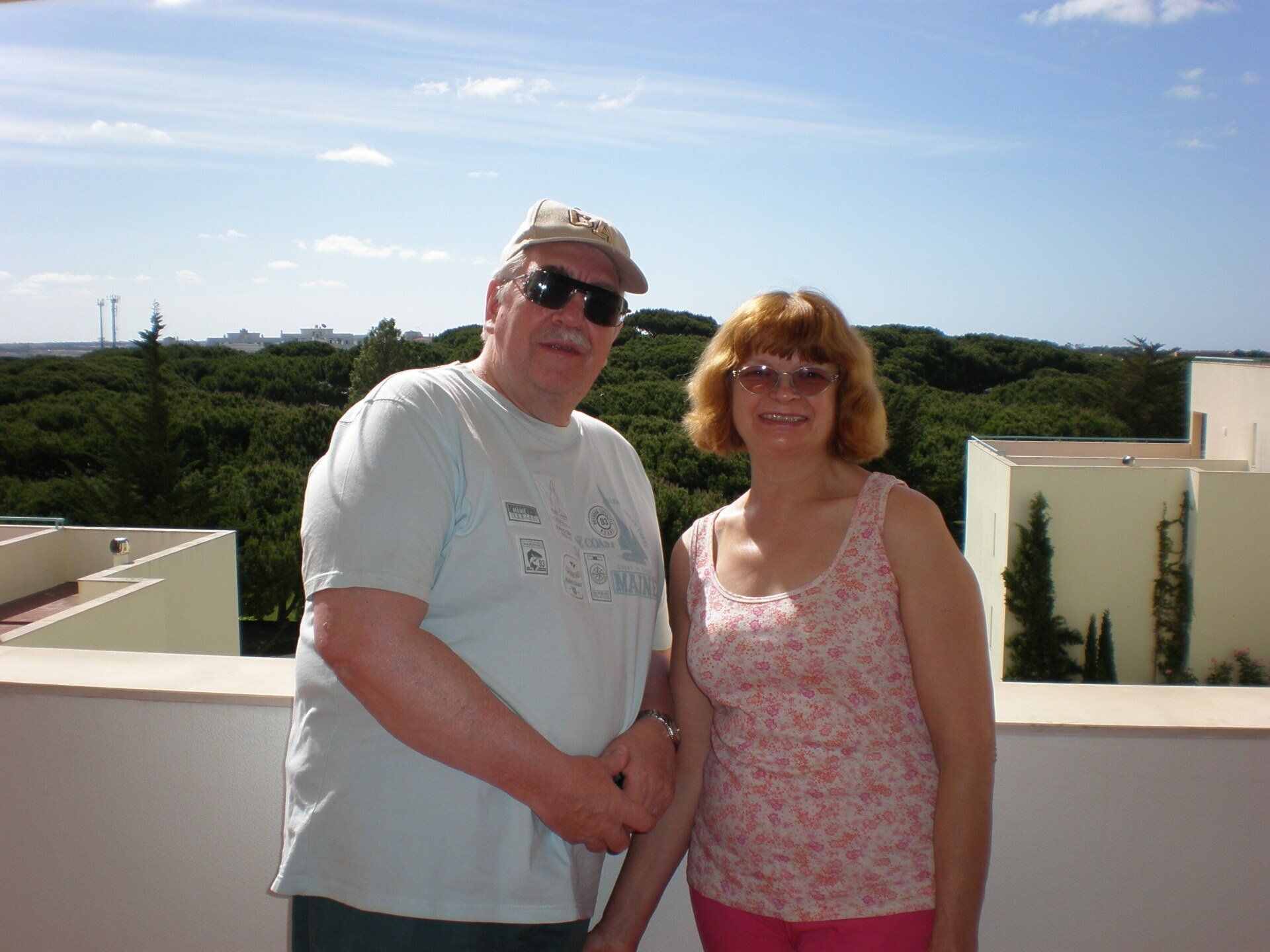 A man and a woman are posing for a picture on a balcony